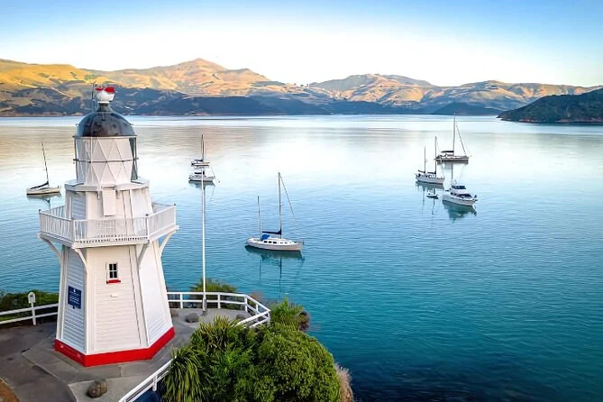 The white Akaroa lighthouse above a calm bay dotted with moored yachts